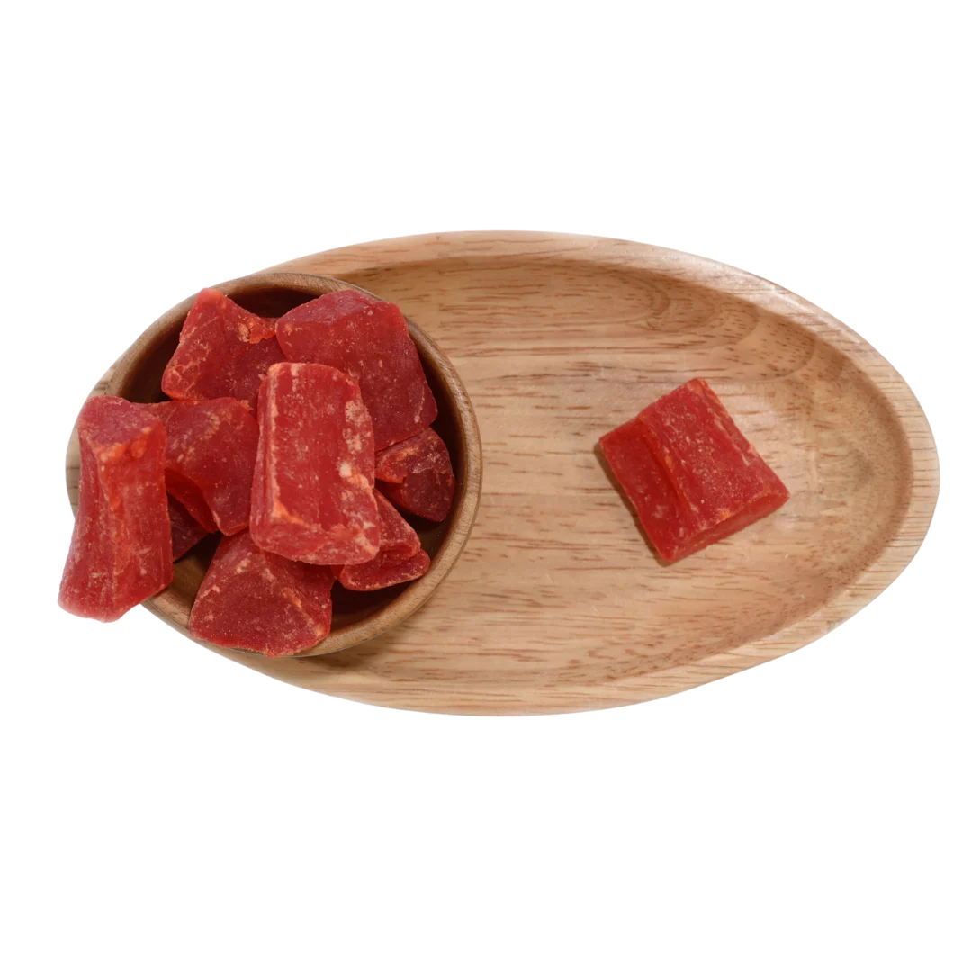 Close-up of vibrant orange dried papaya cubes neatly arranged in a wooden bowl.