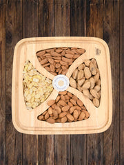 Wooden gift tray containing four sections of almonds – sliced almonds, whole almonds, and almonds in paper shell – placed on a rustic wooden background.