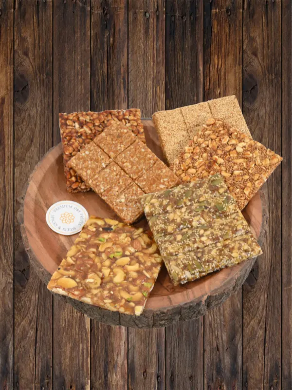 Assorted Indian chikki bars made with peanuts, sesame, jaggery and dry fruits displayed on wooden bowl by House of Rasda.