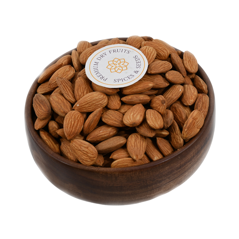 Top view of almonds jumbo in a handcrafted wooden bowl placed on a light fabric surface.