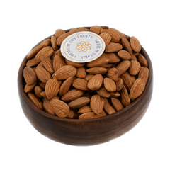 Top view of almonds jumbo in a handcrafted wooden bowl placed on a light fabric surface.