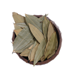 A bowl of dried bay leaves on a wooden kitchen counter, with a House of Rasda product label beside it