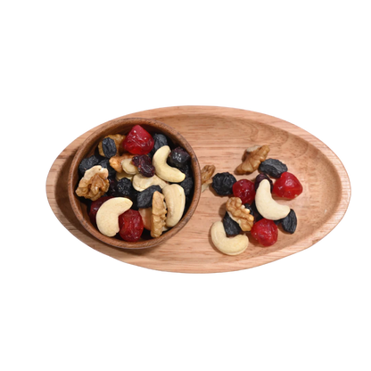 Berry Nutty Trail Mix Wooden platter with a bowl of mixed nuts and dried fruits on a white background