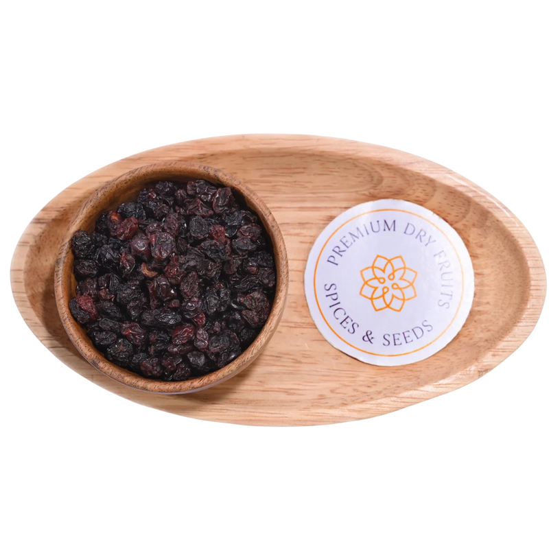 Wooden bowl with dried berries on a wooden tray Black Currants Dried Premium