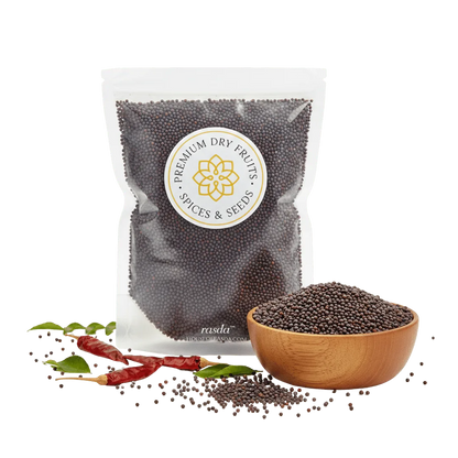 Packaged black mustard seeds with a bowl of seeds and dried red chilies on a white background.