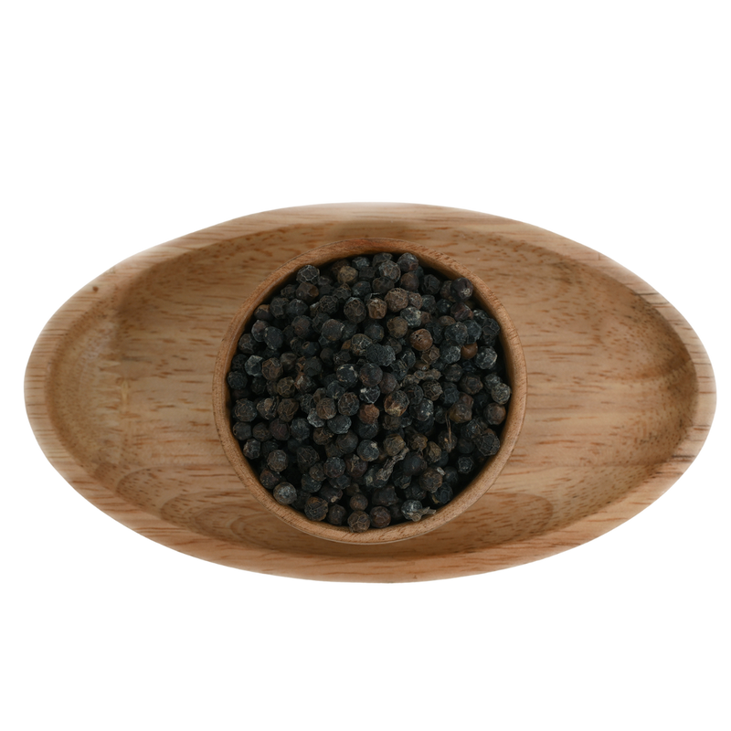 Whole black pepper corns scattered on a wooden Bowl