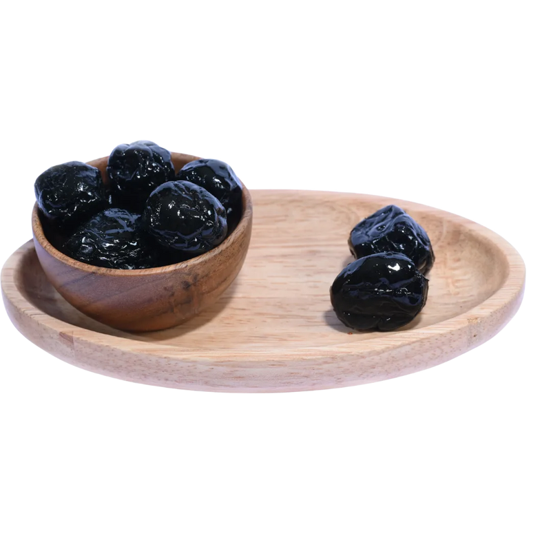Top-down shot of a wooden bowl filled with Black Plums Dehydrated.