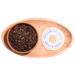 Close-up of small, black sesame seeds, scattered across a surface.