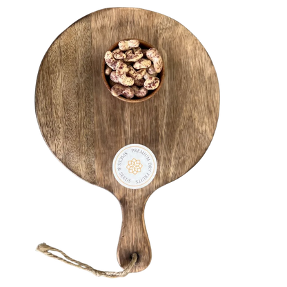 Wooden serving board with a handle and a small bowl of Cashew Nuts Rose Petal on a white background
