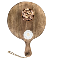 Wooden serving board with a handle and a small bowl of Cashew Nuts Rose Petal on a white background