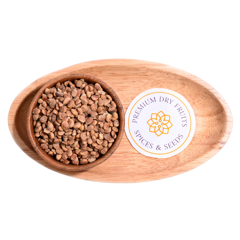 A handful of charoli seeds scattered on a wooden surface, small and brown with smooth textures