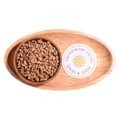 A handful of charoli seeds scattered on a wooden surface, small and brown with smooth textures