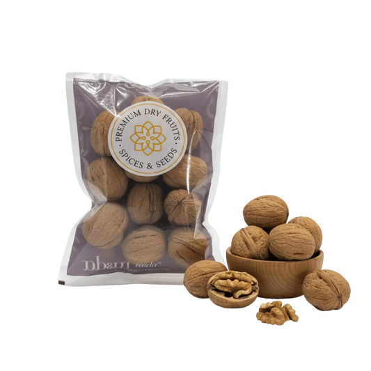 Premium in-shell walnuts (Akhrot) in sealed pack with whole walnuts and kernel shown in wooden bowl.