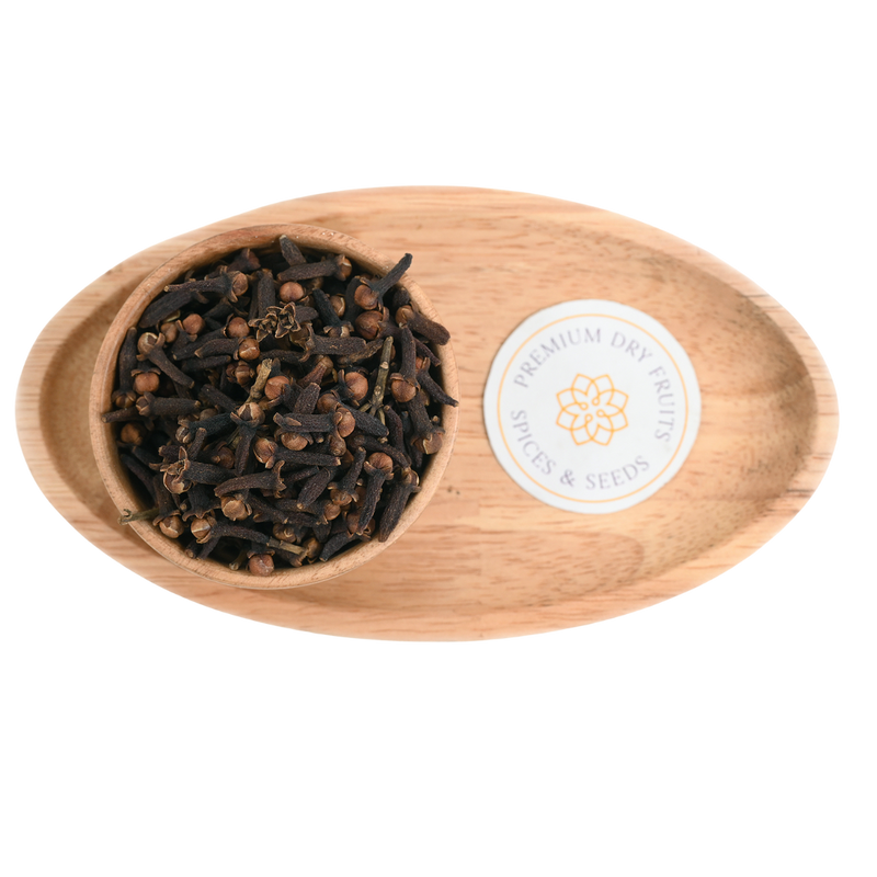 Cloves (Laung) scattered on a wooden background, emphasizing their texture and the characteristic clove bud shape
