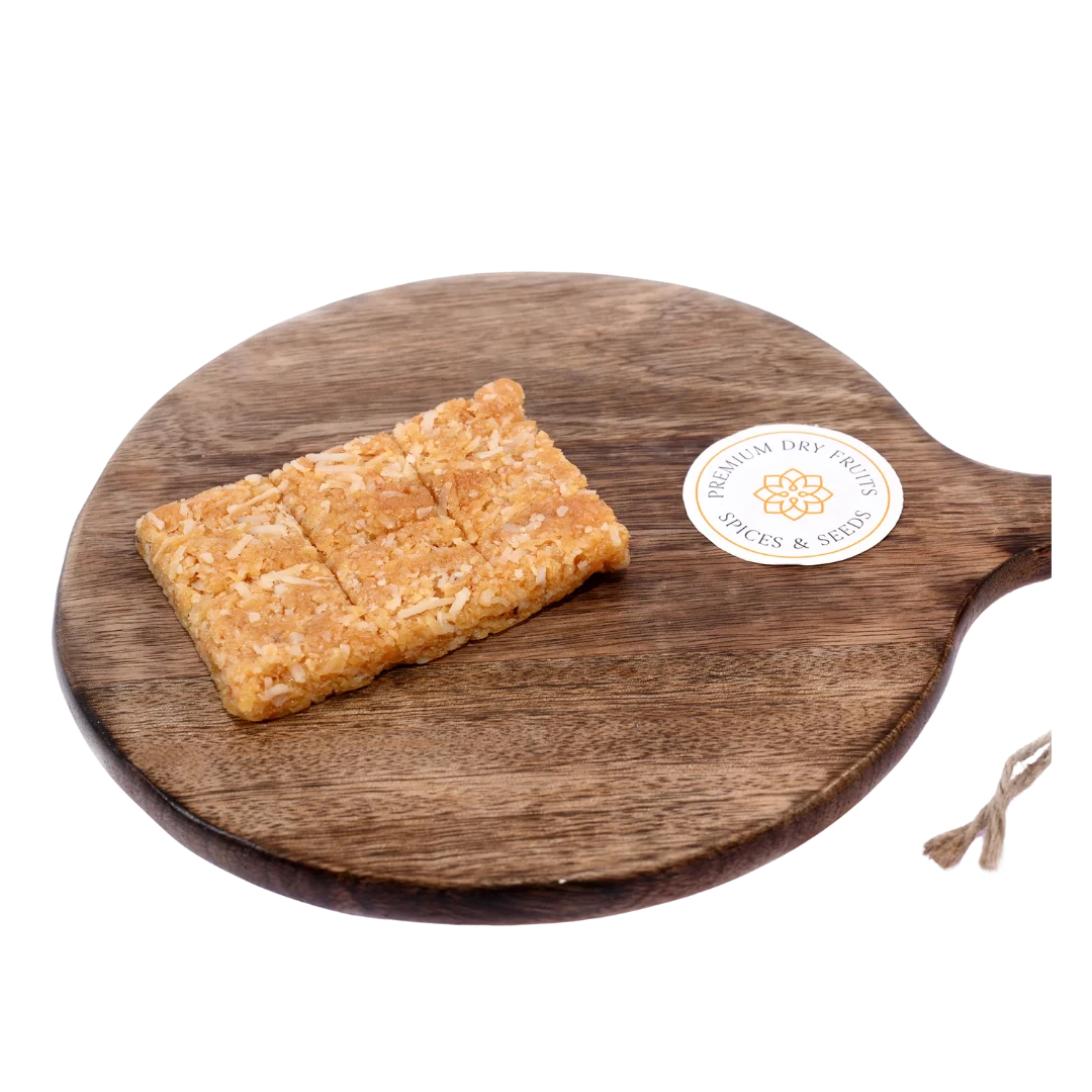 Coconut Chikki on wooden plate delicious Indian jaggery brittle with roasted coconut tasty crunchy snack ideal for