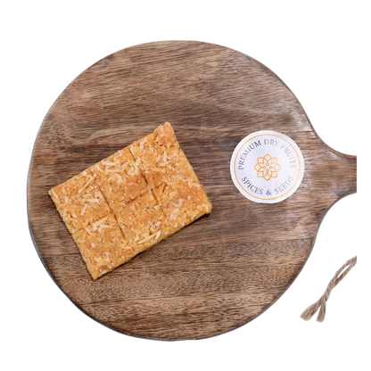 Coconut Chikki on wooden plate traditional Indian sweet made with grated coconut and jaggery healthy crunchy snack