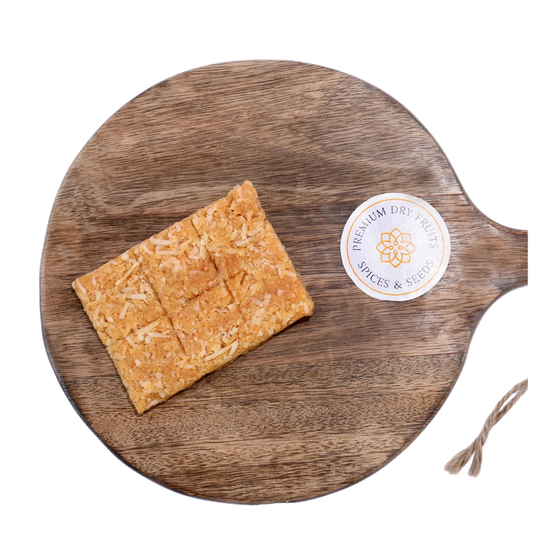 Coconut Chikki on wooden plate traditional Indian sweet made with grated coconut and jaggery healthy crunchy snack perfect for winter and festive season
