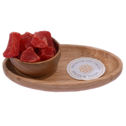 Dried papaya cubes spilling slightly from a wooden bowl, with a soft-focus background.