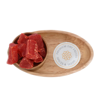 Top view of dried papaya cubes in a small wooden bowl on a rustic surface
