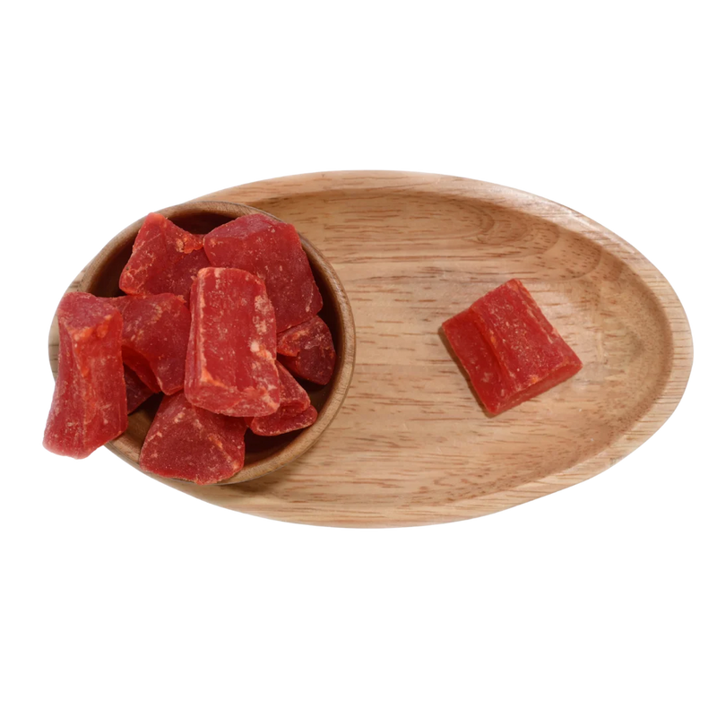 Close-up of vibrant orange dried papaya cubes neatly arranged in a wooden bowl.