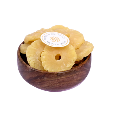 Dried pineapple slices in a wooden bowl on a white background