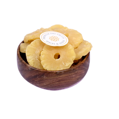 Dried pineapple slices in a wooden bowl on a white background