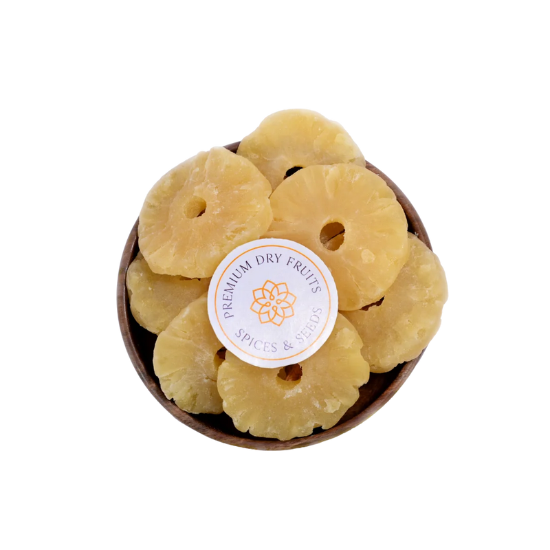 Dried Pineapple slices in a wooden bowl with a label on a white background
