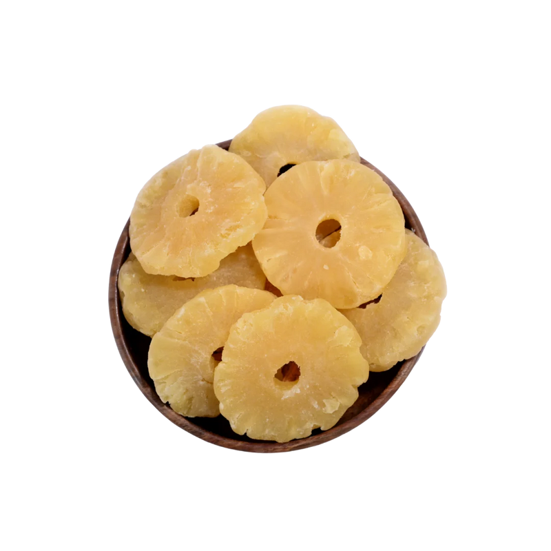 Dried pineapple rings in a wooden bowl on a white background