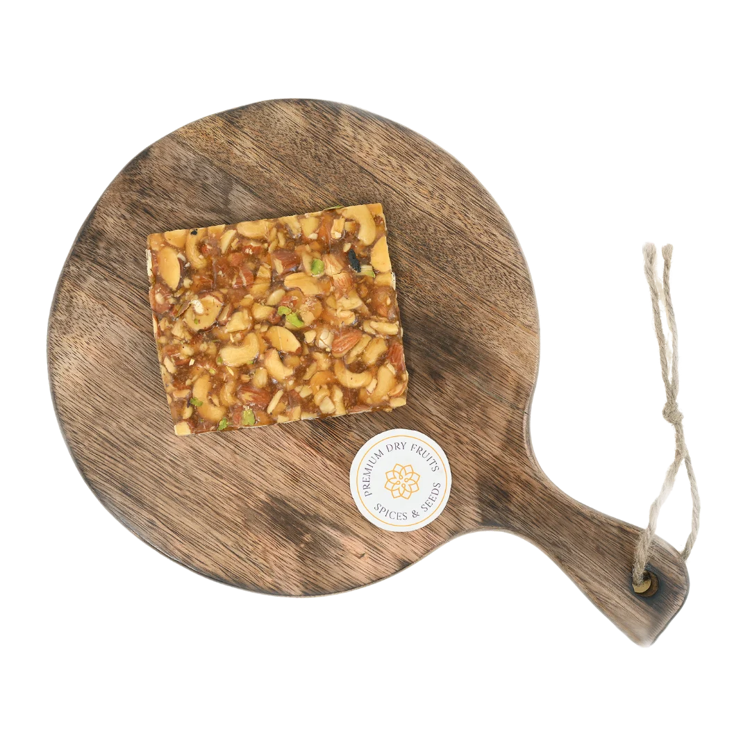 Dry Fruit Chikki on wooden plate traditional Indian sweet made with jaggery almonds cashews and pistachios healthy crunchy snack for winter and festivals