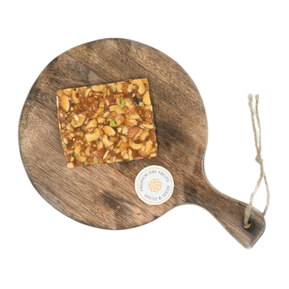 Dry Fruit Chikki on wooden plate traditional Indian sweet made with jaggery almonds cashews and pistachios healthy crunchy snack for winter and festivals