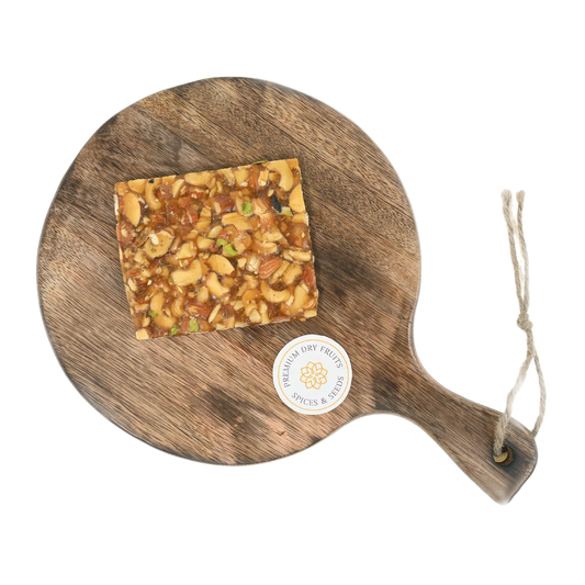 Dry Fruit Chikki on wooden plate traditional Indian sweet made with jaggery almonds cashews and pistachios healthy crunchy snack for winter and festivals