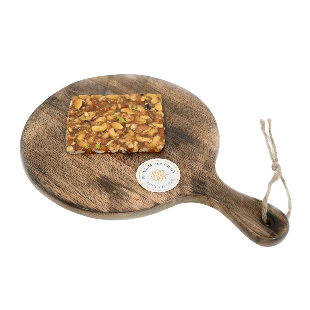 Dry Fruit Chikki on wooden plate premium jaggery sweet loaded with assorted dry fruits almonds cashews pistachios rich crunchy festive snack