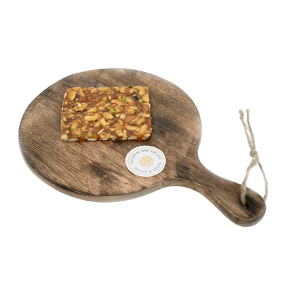 Dry Fruit Chikki on wooden plate premium jaggery sweet loaded with assorted dry fruits almonds cashews pistachios rich crunchy festive snack