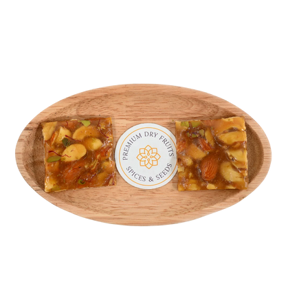 Dry Fruit Chikki on wooden plate crunchy jaggery bar with mixed dry fruits almonds and cashews nutritious Indian sweet ideal for winter and celebrations