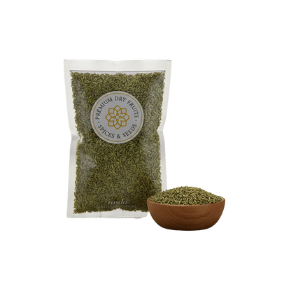 Packaged green fennel seeds with a bowl of spices on a white background