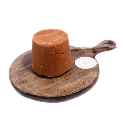 Golden brown Jaggery / Gud pieces in a wooden bowl, showcasing their natural texture and rich sweetness.