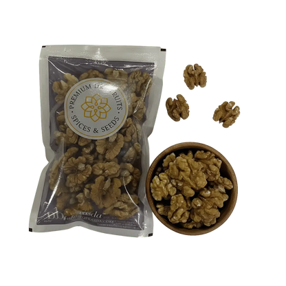Premium Kashmiri walnuts in a bag beside a bowl filled with walnut halves, showcasing their rich texture and quality.