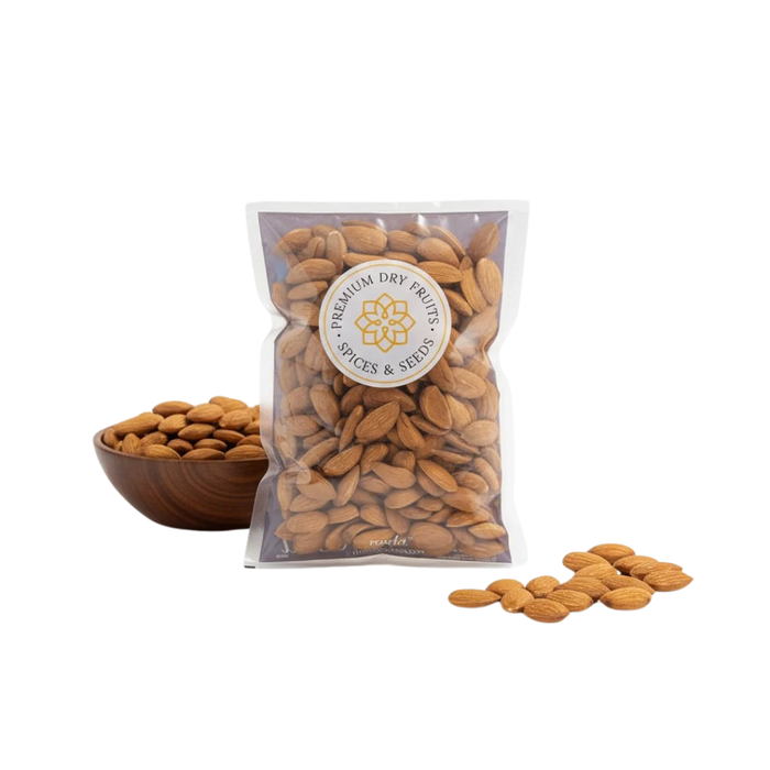 signature mamra almonds 5a grade in a clear bag with a visible Packed brand label, next to a wooden bowl and scattered almonds on a white background.