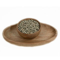 White pepper corns spilling from a wooden bowl onto a table