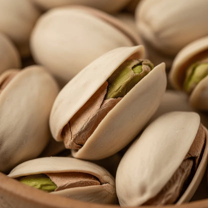 Close-up of pistachios with shells partially open, revealing green kernels.