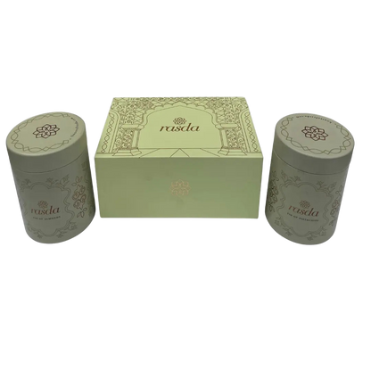 Two cylindrical green containers with a matching box featuring Rasika Dry fruits Gift Box with Tins Rasda branding on a white background.