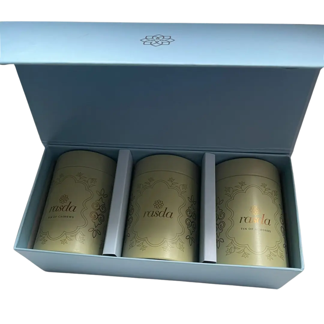 Three gold tea canisters in a blue box with branding. Premium nuts and dry fruits packed in designer airtight tins for