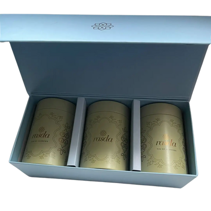 Three gold tea canisters in a blue box with branding. Premium nuts and dry fruits packed in designer airtight tins for