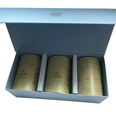 Three gold tea canisters in a blue box with branding. Premium nuts and dry fruits packed in designer airtight tins for festive gifting