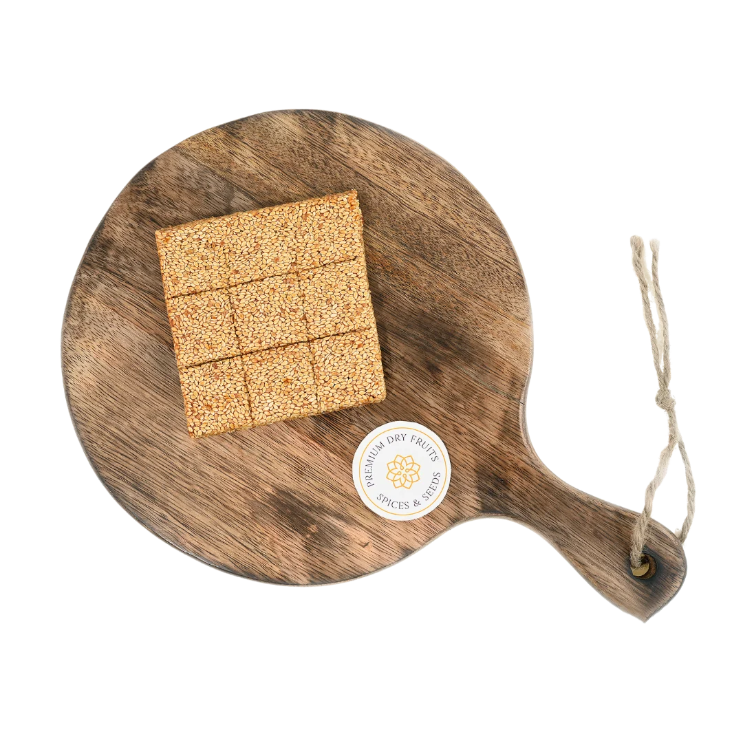 Sesame Chikki or Til Chikki on wooden plate traditional Indian sweet made with jaggery and roasted sesame seeds healthy crunchy snack winter special