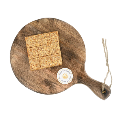 Sesame Chikki or Til Chikki on wooden plate traditional Indian sweet made with jaggery and roasted sesame seeds healthy