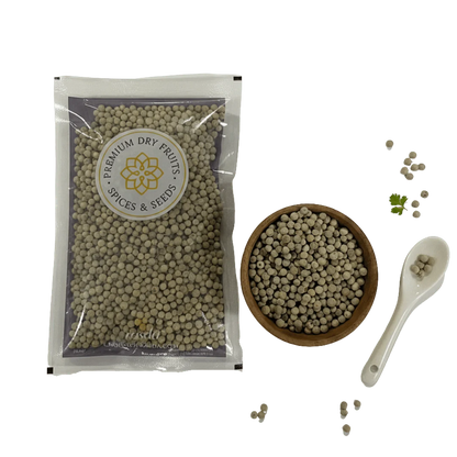 Packaged white peppercorns with a bowl, spoon, and loose peppercorns on a white background.