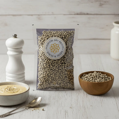 Packaged white pepper with a bowl and pepper on a wooden surface