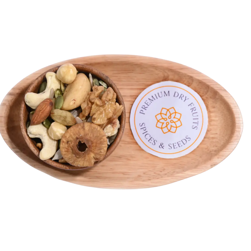 Wooden bowl with Wholesome Nutty Trail Mix assorted dry fruits and spices on a wooden tray.