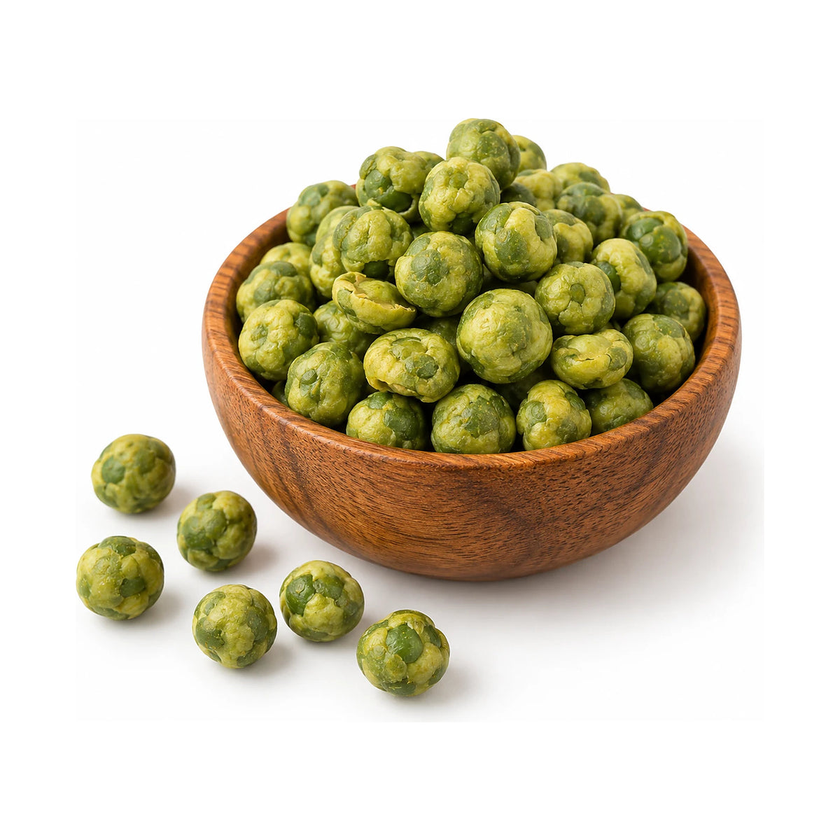 Wasabi coated green peas in a wooden bowl with a few loose peas beside it